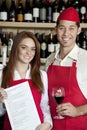 Portrait of young wait staff with wine glass and menu card in bar