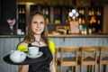 Portrait young waitress standing in cafe. girl the waiter holds in bunches a tray with utensils Royalty Free Stock Photo