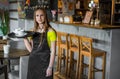 Portrait young waitress standing in cafe. girl the waiter holds in bunches a tray with utensils Royalty Free Stock Photo