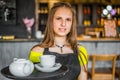 Portrait young waitress standing in cafe. girl the waiter holds in bunches a tray with utensils. Royalty Free Stock Photo