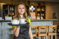 Portrait young waitress standing in cafe. girl the waiter holds in bunches a tray with utensils. Royalty Free Stock Photo