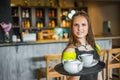 Portrait young waitress standing in cafe. girl the waiter holds in bunches a tray with utensils. Royalty Free Stock Photo