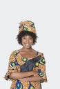 Portrait of young woman in African print attire standing arms crossed over gray background Royalty Free Stock Photo