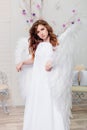 Portrait of a young woman, an angel in a white dress stands wrapped in wings Royalty Free Stock Photo