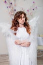 Portrait of a young woman, an angel in a white dress stands wrapped in wings Royalty Free Stock Photo