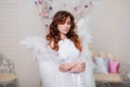 Portrait of a young woman, an angel in a white dress stands wrapped in wings Royalty Free Stock Photo