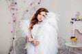 Portrait of a young woman, an angel in a white dress stands wrapped in wings Royalty Free Stock Photo