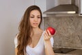 Portrait of a young woman with an apple in her hand in the kitchen Royalty Free Stock Photo