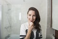 Portrait of young woman applying lipstick in bathroom