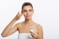 Portrait of young woman applying moisturizer cream on her pretty face. Isolated on white background Royalty Free Stock Photo