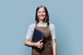 Portrait of young woman in apron holding laptop on blue background Royalty Free Stock Photo