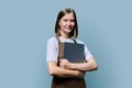Portrait of young woman in apron holding laptop on blue background Royalty Free Stock Photo