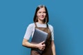 Portrait of young woman in apron holding laptop on blue background Royalty Free Stock Photo