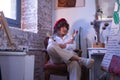 Portrait of young woman, artist, designer and painter with a red beret, sitting with her arms crossed with brushes and Royalty Free Stock Photo