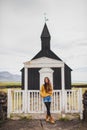 Portrait of young woman on Background of Famous black church of Budir in Iceland