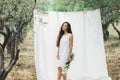 Portrait of young woman on background of white hanging textile cloth in garden Royalty Free Stock Photo