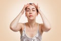 Portrait of a young woman with beautiful skin, tightening the skin on her forehead with her hands. Beige background. Copy space. Royalty Free Stock Photo