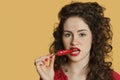 Portrait of a young woman biting red chili pepper over colored background Royalty Free Stock Photo