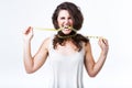 Young woman biting tape measure over white background.