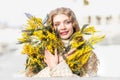 Portrait of a young woman with blond hair holding a bouquet of mimosa in her hands. Spring Royalty Free Stock Photo