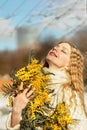 Portrait of a young woman with blond hair holding a bouquet of mimosa in her hands. Spring Royalty Free Stock Photo