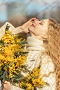 Portrait of a young woman with blond hair holding a bouquet of mimosa in her hands. Spring Royalty Free Stock Photo