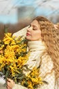 Portrait of a young woman with blond hair holding a bouquet of mimosa in her hands. Spring Royalty Free Stock Photo