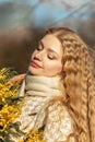 Portrait of a young woman with blond hair holding a bouquet of mimosa in her hands. Spring Royalty Free Stock Photo