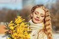 Portrait of a young woman with blond hair holding a bouquet of mimosa in her hands. Spring Royalty Free Stock Photo