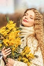 Portrait of a young woman with blond hair holding a bouquet of mimosa in her hands. Spring Royalty Free Stock Photo