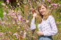 Portrait of the young woman among the blossoming bushes of almonds three-blade