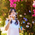 Portrait of Young woman blowing soap bubbles on pink flowers background on the beach. Royalty Free Stock Photo