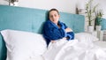 Portrait of young woman in blue bathrobe lying in bed at home Royalty Free Stock Photo