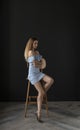 Portrait of a young woman in a blue dress sitting on a high bar stool Royalty Free Stock Photo