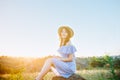 Portrait of young woman in blue romantic dress and straw hat in sun light enjoying summer sunset on nature. Calm and harmony. Royalty Free Stock Photo