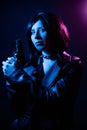 Portrait of a young woman with a bob hairstyle in a black leather jacket and a spiked collar with a gun in her hands Royalty Free Stock Photo