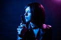 Portrait of a young woman with a bob hairstyle in a black leather jacket and a spiked collar with a gun in her hands Royalty Free Stock Photo