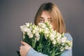 Portrait of a young woman with a bouquet of roses on a gray background. Royalty Free Stock Photo