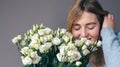 Portrait of a young woman with a bouquet of roses on a gray background. Royalty Free Stock Photo