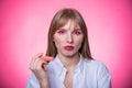 Portrait of a young woman with braces and bright makeup chewing gum on a pink background. Royalty Free Stock Photo