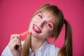 Portrait of a young woman with braces and bright makeup chewing gum on a pink background. Royalty Free Stock Photo