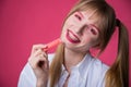 Portrait of a young woman with braces and bright makeup chewing gum on a pink background. Royalty Free Stock Photo