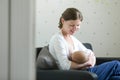 Portrait of a young woman breastfeeding a child on her knees