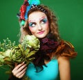 Portrait of young woman with bright creative make up holding dry flowers, studio shoot over green background Royalty Free Stock Photo
