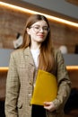 Portrait of a young woman broker with a folder in her hands in the office, startup