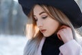 Portrait of a young woman with brown eyes with lips with blond hair with beautiful make-up in an elegant black hat Royalty Free Stock Photo