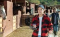 Portrait of young woman with brushes in her hands for cleaning and caring for horses at horse farm