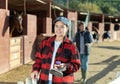 Portrait of young woman with brushes in her hands for cleaning and caring for horses at horse farm