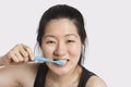 Portrait of a young woman brushing her teeth over light gray background Royalty Free Stock Photo