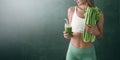 Portrait of a young woman with a bunch of celery in one hand and a glass of celery juice in the other. dark background, studio